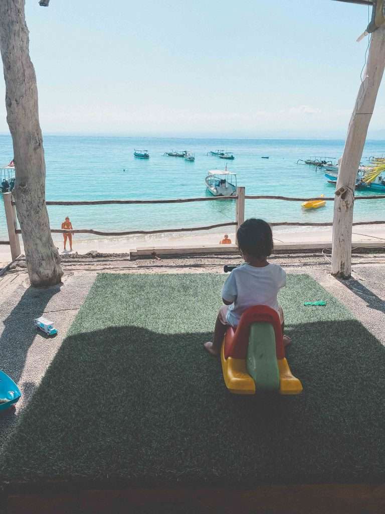 mushroom bay child overlooking the bay fishing boats in crystal clear waters best beach on nusa lembongan