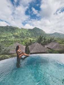 Woman relaxing by infinity pool with the view of sleeping gajah mountains in the Sidemen Bali area