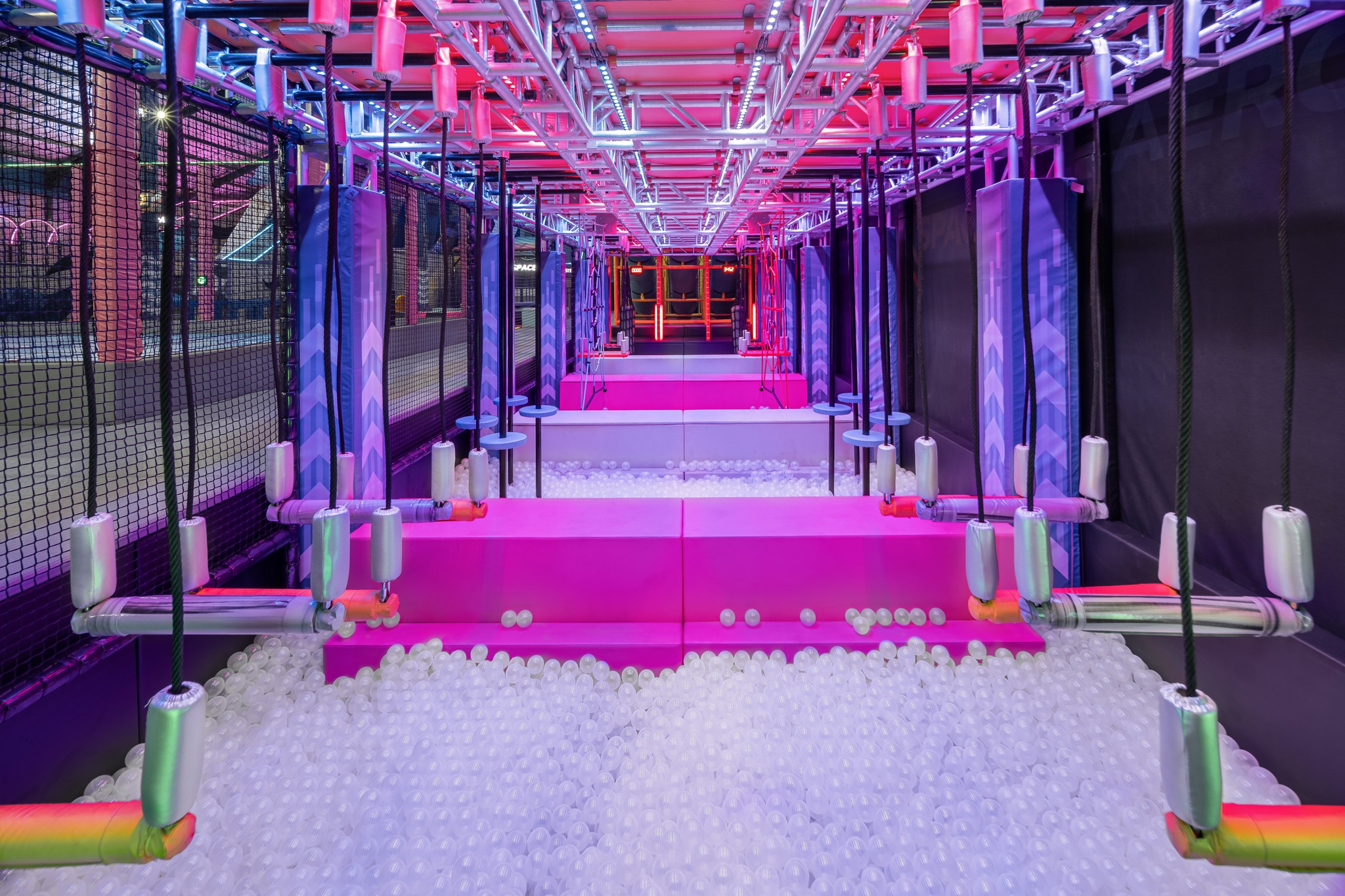 A brightly lit indoor obstacle course with neon lights, rope swings, padded platforms, and ball pits—perfect for a family holiday in Bali or anyone searching for exciting things to do in Bali with kids.