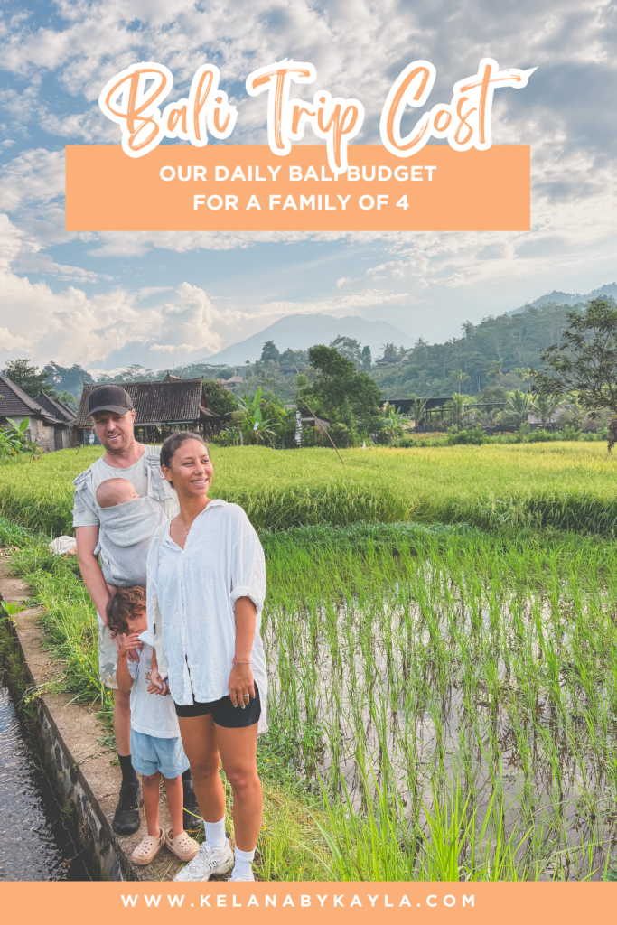 A family of four stands beside a lush green rice field in Bali, with mountains in the background. Text reads: Bali Trip Costs—Our Daily Bali Budget for a Family of 4. www.kelanabykayla.com.