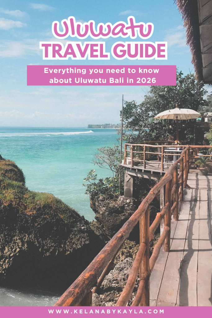 A wooden deck with a table and umbrella overlooks turquoise ocean waters and cliffs in Uluwatu, Bali, under a blue sky. Text reads: Uluwatu Travel Guide — everything you need to know about Uluwatu Bali in 2026, your essential uluwatu travel guide for the perfect getaway.